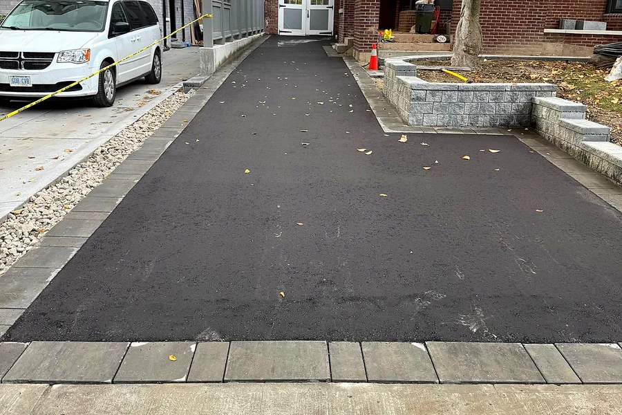 Long asphalt driveway with a paver border